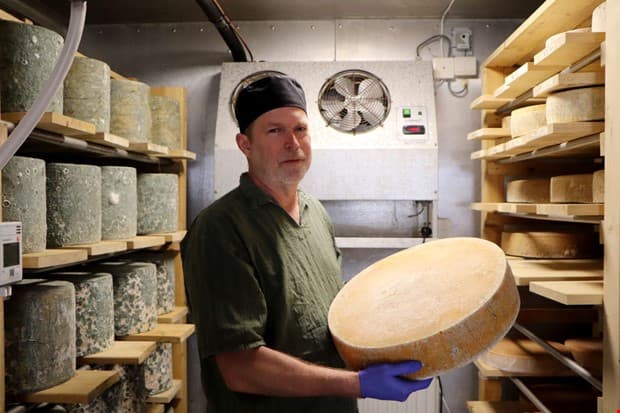 Håkan visar upp en rund ost i lagringsrummet